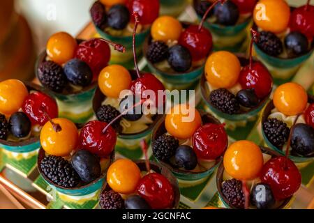 Quatre fruits différents, disposés dans de petits bols sur une table de buffet décorée pour une fête. Banque D'Images