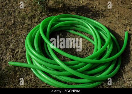 Green House pipe enroulé autour à la maison jardin de pelouse après l'arrosage. Fabriqués en PVC, tuyaux longs tressés. Pose sur l'herbe Banque D'Images