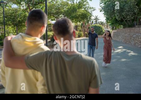 Des amis attendent leur arrivée. Ils arrivent très heureux à eux. Ils se saluent mutuellement lorsqu'ils arrivent. Ils portent du col Banque D'Images