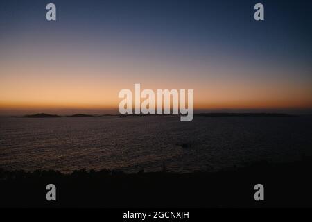 Vue sur le coucher du soleil depuis Garrison Hill en direction de St Agnes, avec maison au bord de la mer, île de St Mary, îles de Scilly, Cornouailles, Angleterre,Royaume-Uni, juillet 2021 Banque D'Images