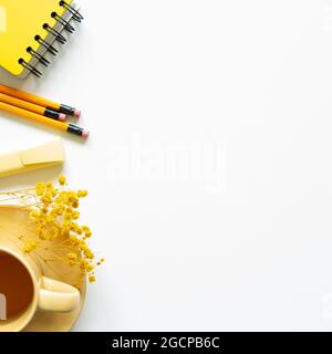 Carnet, tasse de thé, stylo, fleur sèche sur fond blanc. Vue du dessus, espace de copie. Lieu de travail et d'étude Banque D'Images