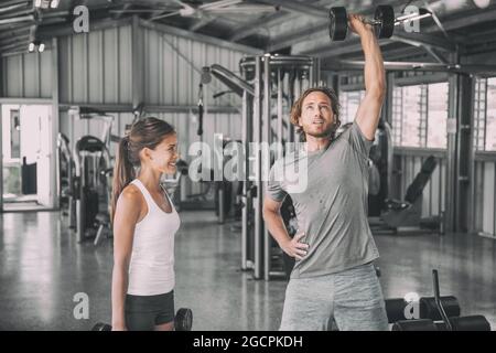 Fitness gym entraîneur personnel entraîneur d'entraînement asiatique femme avec des poids libres dumbbbell bicep boucles d'entraînement parler avoir plaisir partenaire d'exercice. Poser l'homme Banque D'Images