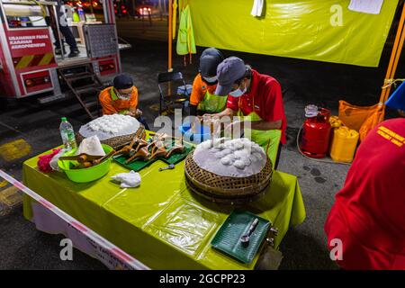 Marché nocturne de la cuisine de rue à Putrajaya, près de Kuala Lumpur. Les jeunes hommes qui font de l'Idiyappam ou de la trémie à cordes, un plat traditionnel de nouilles de riz de l'Inde. Banque D'Images