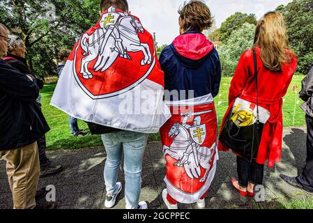 Les manifestants ont été drapés par les drapeaux de l'opposition et leur dos à l'ambassade du Bélarus pendant la manifestation.pendant exactement un an, les manifestations civiles pacifiques au Bélarus ont été violemment écrasées. Plus de 600 civils innocents sont emprisonnés et torturés. La critique du gouvernement n'est pas tolérée. Le régime du président Alexandre Loukachenko le place au pouvoir depuis 1994 et est aujourd’hui le plus long dictateur d’Europe. La manifestation d'aujourd'hui était destinée à être symbolique et pas grand en nombre et les noms des 600 sont lus. La voie des drapeaux porte les noms des persécutés et est située en face du B Banque D'Images