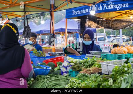 Marchands de légumes sur un marché frais à Putrajaya, près de la capitale Kuala Lumpur. La femme islamique avec hijab vend des légumes. En raison de Covid-19 elle porte f Banque D'Images