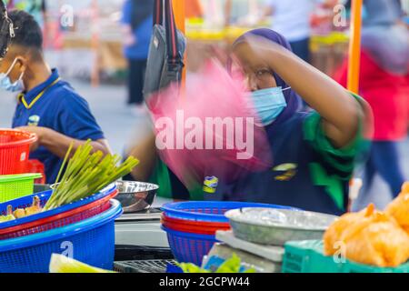 Marchands de légumes sur un marché frais à Putrajaya, près de la capitale Kuala Lumpur. Femme islamique avec hijab derrière un plastique rose flou Banque D'Images