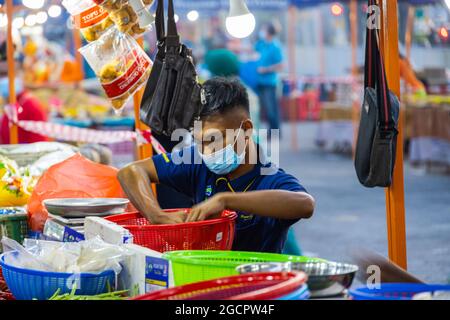 Marchands de légumes sur un marché frais à Putrajaya, près de la capitale Kuala Lumpur. Un jeune homme avec masque met les légumes sur une balance Banque D'Images