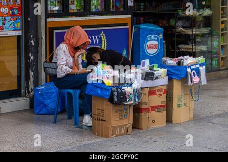 Vendeurs de rue sur les routes de Kuala Lumpur. Les marchandises sont vendues à partir de boîtes en carton. Masques, livres anciens et autres produits d'occasion. Femme joue sur le p Banque D'Images