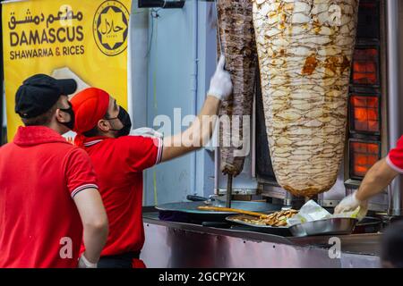 Restaurant de cuisine de rue Kebab dans le centre-ville de Kuala Lumpur. Deux hommes en chemise rouge ont coupé la viande d'agneau de la brochette de kebab. Célèbre restaurant de rue Shawarma à Ma Banque D'Images