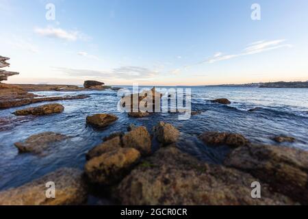 Littoral rocheux autour de la plage de Bondi, Sydney, Australie. Coucher de soleil près de la célèbre plage de surfeurs. Coucher de soleil sur l'océan pacifique. Le soleil se reflète dans le smoot Banque D'Images