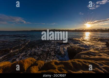 Littoral rocheux autour de la plage de Bondi, Sydney, Australie. Coucher de soleil près de la célèbre plage de surfeurs. Coucher de soleil sur l'océan pacifique. Le soleil se reflète dans le smoot Banque D'Images