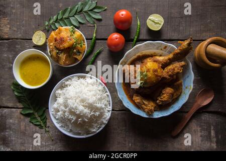 Vue depuis le haut de la nourriture indienne ou repas avec frites de pommes de terre, poulet curry de riz, lentilles, papayes et condiments. Plat non végétarien. Banque D'Images