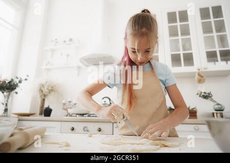 Portrait d'une petite fille blonde de l'adolescence portant un tablier dans la cuisine Banque D'Images