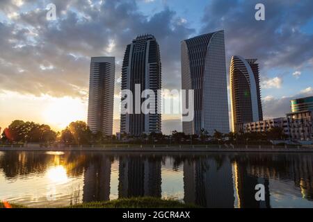 Gratte-ciel au coucher du soleil, en face d'un lac avec des reflets des bâtiments. Magnifique coucher de soleil coloré derrière les maisons hautes. Quartier des affaires ilumina Banque D'Images