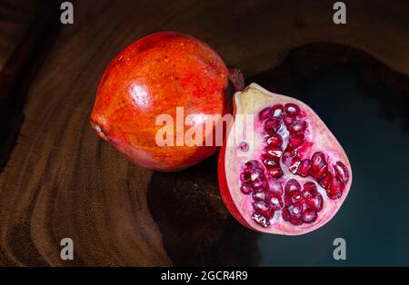 Un grenade près d'une table en bois tropical. Macro photographie des graines et du fruit entier. Structure du bois en arrière-plan. Détai Banque D'Images