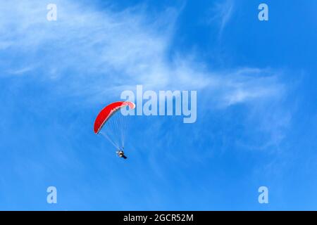 Paramoteur volant dans un ciel bleu. Homme d'aventure pilote de sport extrême actif volant dans le ciel avec parachute de planeur de moteur paramoteur Banque D'Images