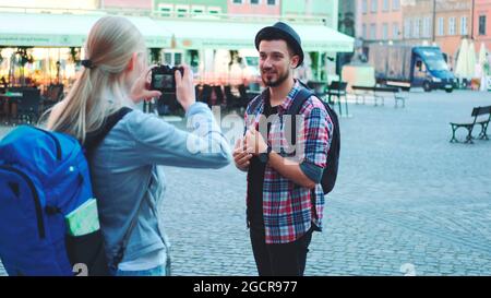 Couple de touristes faisant des photos avec photo appareil photo sur la place du marché historique. Homme posant et femme prenant des photos. Banque D'Images