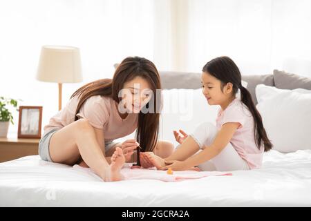 Bonne mère et fille appliquant du vernis à ongles dans la chambre Banque D'Images