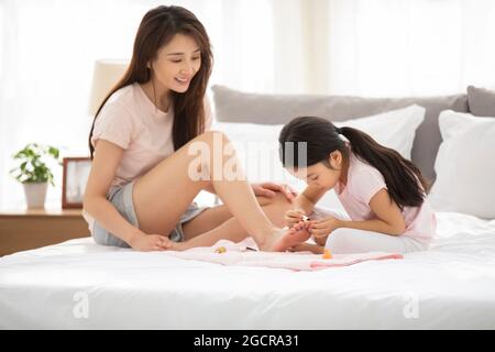 Bonne mère et fille appliquant du vernis à ongles dans la chambre Banque D'Images