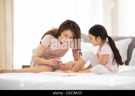 Bonne mère et fille appliquant du vernis à ongles dans la chambre Banque D'Images