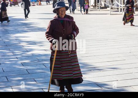 Lhassa, Tibet, Chine - 15 novembre 2019 : ancienne tibétaine sur des béquilles sur la place du temple de Jokhang. Pauvre femme âgée à la recherche dans la Tibe traditionnelle Banque D'Images