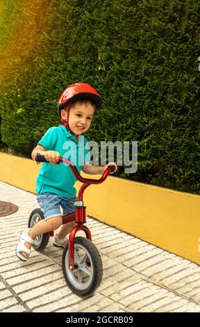 preschooler souriant et jouant avec un petit vélo lors d'une journée ensoleillée d'été Banque D'Images