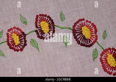 Fleur en point de pistil, motif brodé à la main de fleurs en point de pistil et feuilles courtes en point à chevrons sur le tissu rose, broderie en tissu Banque D'Images