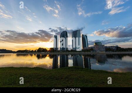 Gratte-ciel au coucher du soleil, en face d'un lac avec des reflets des bâtiments. Magnifique coucher de soleil coloré derrière les maisons hautes. Quartier des affaires ilumina Banque D'Images