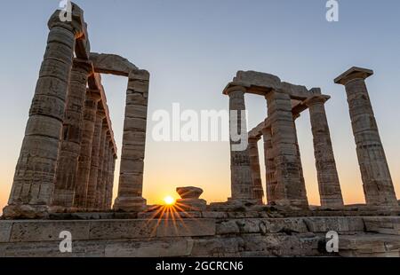 Coucher de soleil coloré et étonnant au Temple de Poséidon, site archéologique de Sounion, Attique. Cap Sounion, Grèce. Un coucher de soleil derrière la citadelle sur une colline Banque D'Images