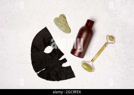 Kit d'auto-soins. Rouleau de visage, grattoir de guasha de masseur, bouteille d'huile cosmétique et masque facial . Pose à plat Banque D'Images