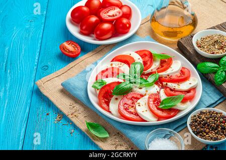 Salade Caprese aux tomates et au fromage mozzarella sur fond bleu. Banque D'Images