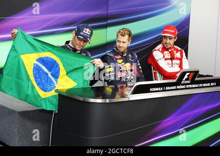 Mark Webber (AUS) Red Bull Racing, célébrant son dernier GP, détient un drapeau brésilien, signé par Bernie Ecclestone (GBR) CEO Formula One Group (FOM) et tous les pilotes, aux côtés de Sebastian Vettel (GER) Red Bull Racing (Centre), et Fernando Alonso (ESP) Ferrari, (à droite). Grand Prix brésilien, dimanche 24 novembre 2013. Sao Paulo, Brésil. Banque D'Images