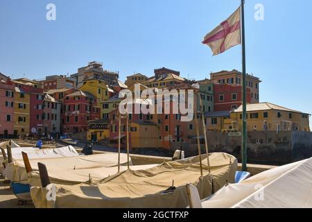 Une rangée de bateaux des pêcheurs amena à terre le long du quai de l'ancien village de pêcheurs avec un drapeau de la ville de Gênes Banque D'Images