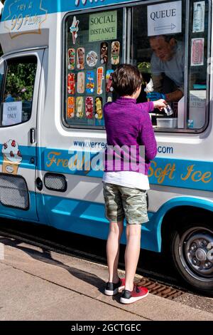 Un enfant en vêtements d'été achète une crème glacée à une camionnette de glace par temps ensoleillé. Cambridge, Royaume-Uni Banque D'Images