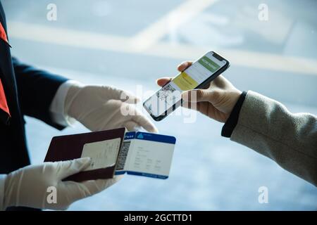 Gros plan d'une femme voyageur montrant son passeport de vaccination au téléphone à un préposé au sol à l'aéroport. Une femme s'est présente à l'aéroport lors d'une pandémie avec Banque D'Images