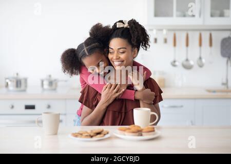 Fille noire émotive qui embrasse sa maman heureuse Banque D'Images