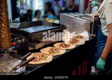 Préparation du shawarma turc. Tortillas prêts à l'emploi avec concombres et garnitures attendent que le cuisinier ajoute de la viande frite hachée et verse la sauc Banque D'Images