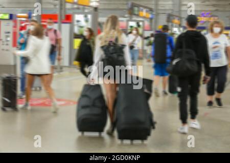 Passagers de train, en circulation publique, à la gare, en passant le long des voies ferrées. Femme aux cheveux justes avec de gros bagages au milieu. Banque D'Images