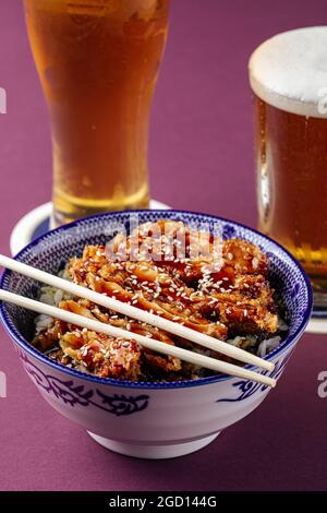 Riz au poulet Katsuson avec bière sur fond violet Banque D'Images