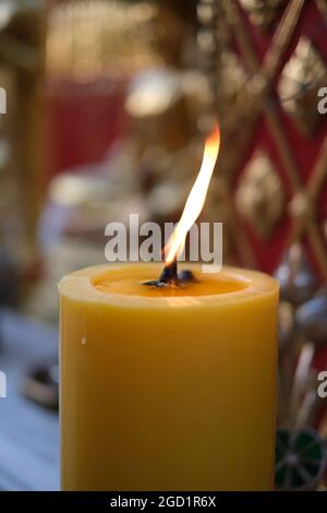 Une bougie épaisse éclairée sur fond de symboles religieux dans un temple bouddhiste au nord de la Thaïlande Banque D'Images