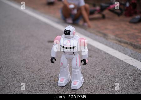 Un robot jouet, radiocommandé par une fille, se déplace sur la route Banque D'Images