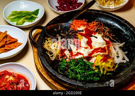 Bibimbap de bœuf chaud coréen servi dans une marmite en pierre de dolsot avec des plats d'accompagnement en banchan Banque D'Images