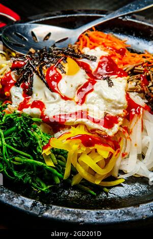 Bibimbap de bœuf chaud coréen servi dans une marmite en pierre de dolsot avec des plats d'accompagnement en banchan Banque D'Images