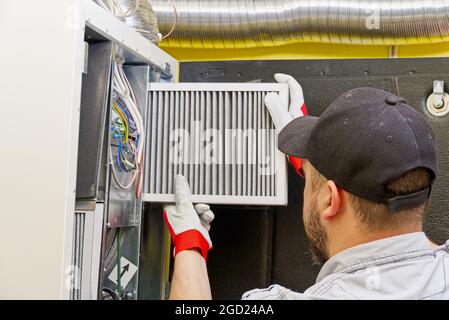 Le technicien d'entretien HVAC change le filtre à air sale dans le système de ventilation central Banque D'Images