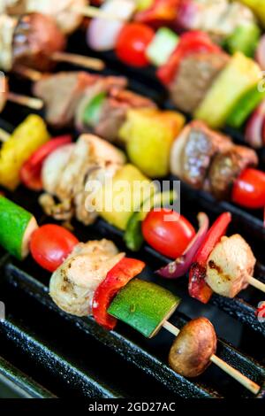 Griller des brochettes de kebab et de steak de poulet avec des oignons rouges, des poivrons et des tomates de raisin Banque D'Images