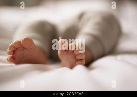 Mise au point sélective des pieds d'un bébé endormi - bébé endormi mignon barefooted sur un lit blanc lumineux Banque D'Images