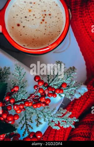Tasse de café avec décor rouge d'hiver et baies, pose plate saisonnière confortable Banque D'Images