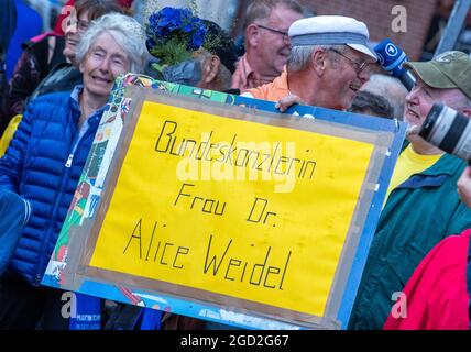 Schwerin, Allemagne. 10 août 2021. Un supporter de l'AfD tient une affiche lisant « le chancelier Dr. Alice Weidel » et se tient en face de la scène au début de la tournée de campagne de l'AfD. Le parti entre dans la campagne électorale avec le slogan "Allemagne. Mais normal." dans la campagne électorale. Credit: Jens Büttner/dpa-Zentralbild/dpa/Alay Live News Banque D'Images