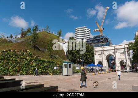 Londres, Royaume-Uni. 10 août 2021. Une femme passe son chien devant la butte de Marble Arch, rouverte aux visiteurs qui n'auront pas à payer pour monter en août. La butte qui a coûté environ 2 millions de livres sterling au conseil de Westminster a été fermée après de fortes critiques de la part des visiteurs à la fin du mois de juillet. le conseil s'est excusé en admettant que «il n'était manifestement pas prêt». Des changements sont encore en cours à l'artefact à l'angle d'Oxford Street et de Park Lane et une aire de jeux et un café qui étaient censés avoir été créés à l'intérieur n'avaient pas été commencés la semaine dernière. Crédit : SOPA Images Limited/Alamy Live News Banque D'Images