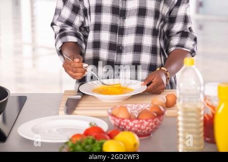 Gros plan de la femme afro-américaine qui murmure des œufs à l'aide d'une fourchette : concept de cuisine Banque D'Images